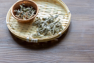 Close-Up of Dried Sage Tea in a Copper Bowl on a Wooden Table
