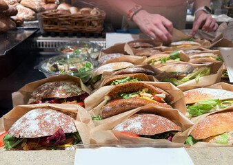 Row of freshly wrapped club sandwiches on cafe counter.