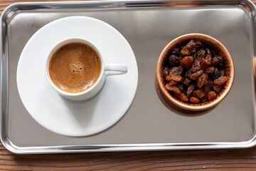 Close-Up of Traditional Turkish Coffee in a White Cup on a Metal Tray with Dried Grapes in a Copper Dish

