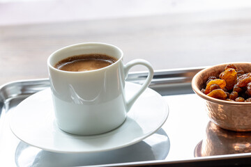 Close-Up of Traditional Turkish Coffee in a White Cup on a Metal Tray with Dried Grapes in a Copper Dish
