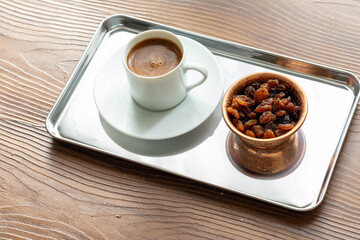Close-Up of Traditional Turkish Coffee in a White Cup on a Metal Tray with Dried Grapes in a Copper Dish
