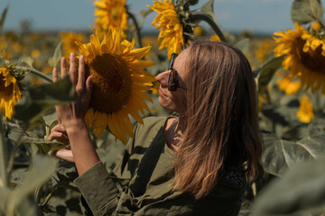 A girl in a pink skirt and a white T-shirt walks through a field of blooming yellow sunflowers. A woman dances, rejoices, smiles, enjoys life, warmth, summer, the sun. High quality FullHD footage