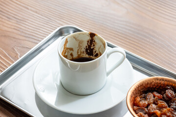 Close-Up of Traditional Turkish Coffee in a White Cup on a Metal Tray with Dried Grapes in a Copper Dish
