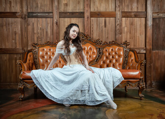 Beautiful sensual woman wears vintage underwear sitting on the brown leather sofa