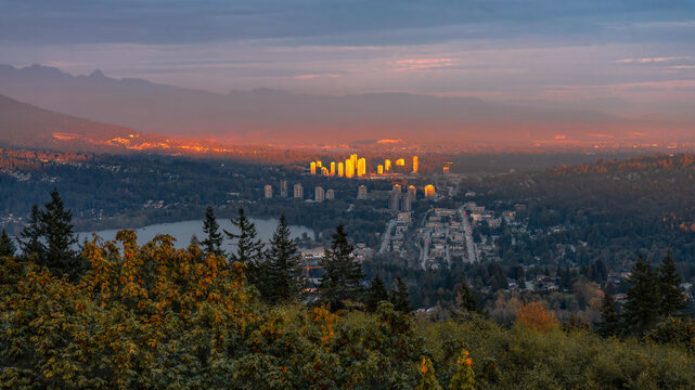 Aerial view of Fraser Valley, BC, Canada with setting sun highlighting high-rise buildings in Coquitlam town centre. - Powered by Adobe