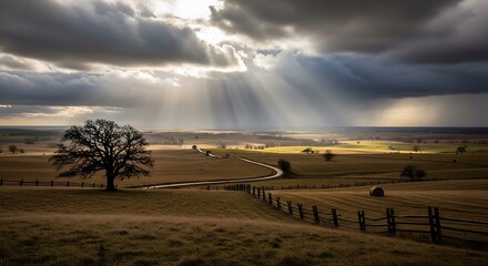 Obraz premium Dramatic landscape with sun rays breaking through cloudy sky over rural fields