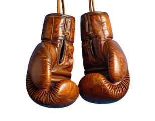 A pair of aged brown leather boxing gloves hanging against a black background