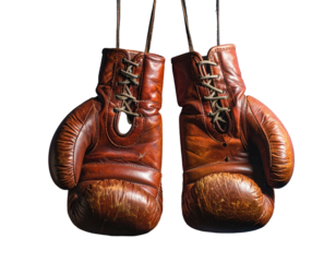 Close-up shot of two aged, leather boxing gloves suspended against a stark black backdrop