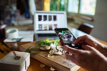 Young woman photographing handmade jewelry