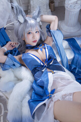 Alluring cosplayer with silver hair and striking blue eyes, adorned in an elegant blue and white...