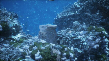 Beneath the crystal blue waves, an ancient stone column rests among vibrant corals and lively fish. Sunlight filters through the water, creating a serene underwater landscape.