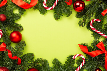 Christmas tree branches with festive decoration on color background, top view