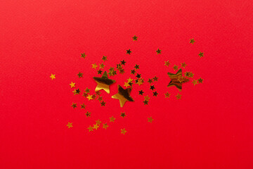 Golden star shape confetti on color background, top view