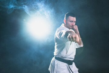 Strong man fighter in white kimono for karate martial arts with black belt preparing for fight...