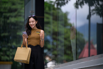 Happy woman shopping online using smartphone and credit card