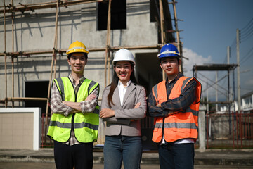 Team of engineers and contractors standing proudly at a housing estate construction site, showcasing teamwork and confidence in project success