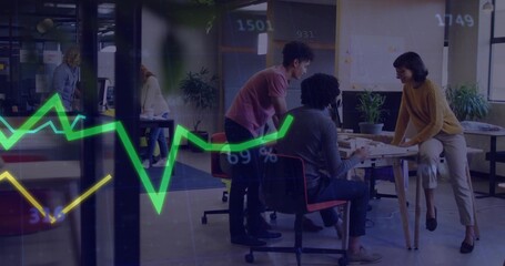 Collaborating four coworkers leaning over table in open-plan office, with documents and notebooks
