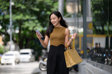 Happy woman shopping and checking phone in city