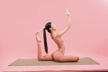 A poised woman on a yoga mat gracefully arches leg raised hand raised in a perfect ok