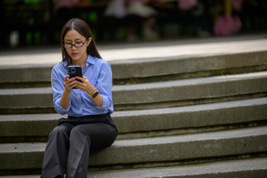 Asian woman businesswoman sitting on stairs using smartphone