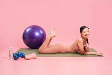Radiant woman on a mat surrounded by fitness gear smiles brightly during her exercise routine