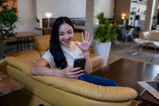 Young woman waving hand during video call on smartphone