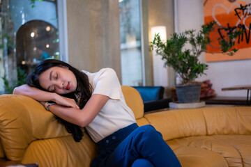 Obraz premium Asian woman sleeping on couch feeling relaxed and tired