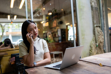Young woman having concerned phone call working remotely