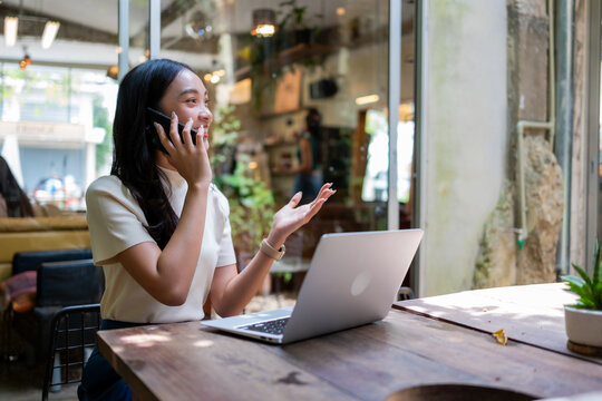 Young woman taking phone call working remotely in cafe