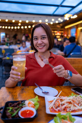 Young woman enjoying dinner and beer at an outdoor restaurant