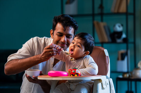 Indian Father and infant boy share bonding moment during mealtime on carpeted floor in home