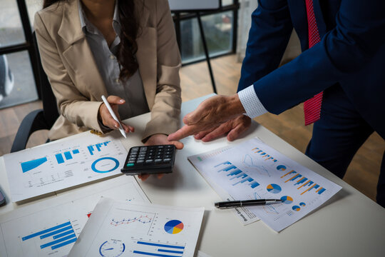 Business people analyzing financial data with calculator and reports