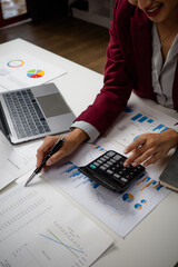 Businesswoman analyzing financial data using calculator and budget charts