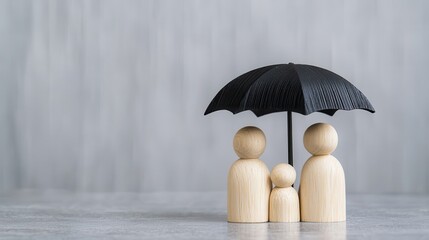 A wooden family figurine trio stands under a black umbrella, symbolizing protection and togetherness against a soft, blurred backdrop.