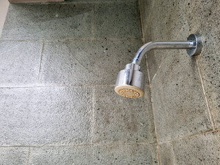 ​A close-up shot focuses on a modern, chrome shower head fixture extending from a wall covered in...