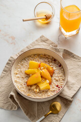 Oatmeal with peaches and nuts  in a bowl on a marble background with honey,