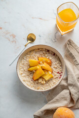 Oatmeal with peaches and nuts  in a bowl on a marble background with honey
