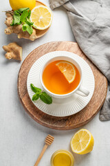 Tea with lemon, ginger, honey, and mint in a cup on a light background