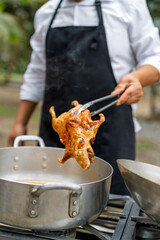 Chef holding traditional fried guinea pig with tongs
