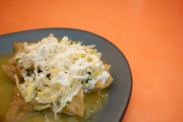 Plano a detalle de unos chilaquiles verdes con crema