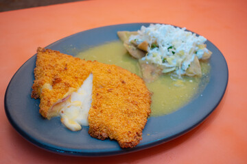 Pechuga de pollo empanizada acompañada de chilaquiles verdes