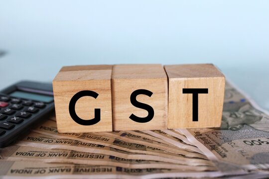 Goods and Services Tax concept, Wooden block with a GST word on stacked coins - Business Concept