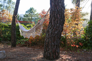 White cloth hammock hanging between two trees at sunset in a mountain village