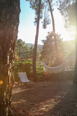 White cloth hammock hanging between two trees at sunset in a mountain village