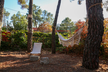 White cloth hammock hanging between two trees at sunset in a mountain village
