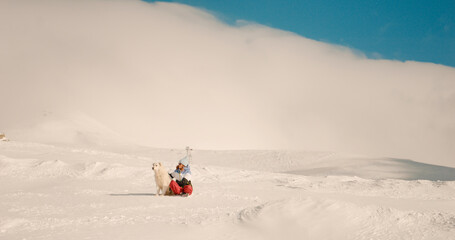 Female training her pet to stay still in nature on calm winter day. Cloudy sky in mountains and...