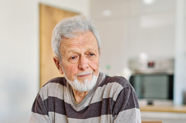 Portrait of a serious sad mature old man at home