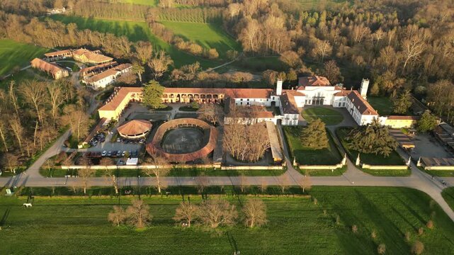 Estate in Lush Valley: An aerial perspective of a grand estate, showcasing a harmonious blend of architectural elegance amidst a verdant valley, with manicured gardens and surrounding woodlands. 