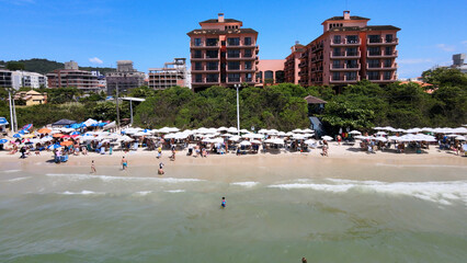 Aerial view of Jurere International beach in Florianopolis, Santa Catarina, luxury homes, beach clubs, high-end residences facing the sea on a luxurious tourist beach sand crowded people and umbrellas