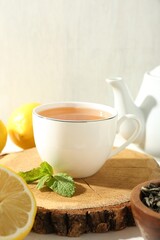 Aromatic tea in cup, lemons, mint and teapot on table, closeup